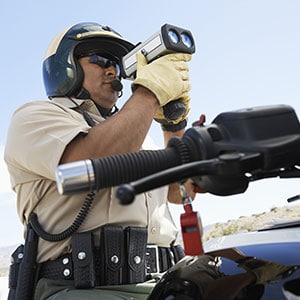 A police officer on a motorcycle using a speed checking camera.