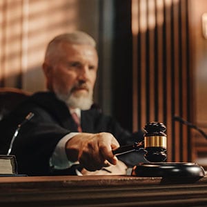 A judge in a courtroom, holding a gavel in hand.